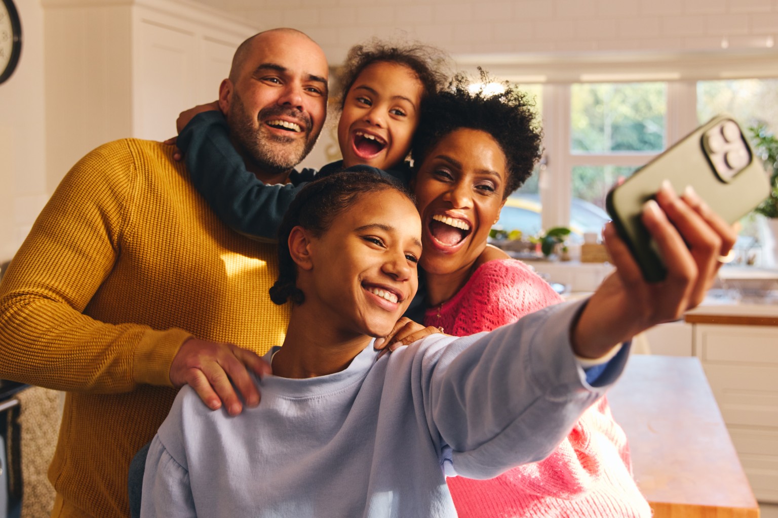 Family taking selfie together in kitchen.