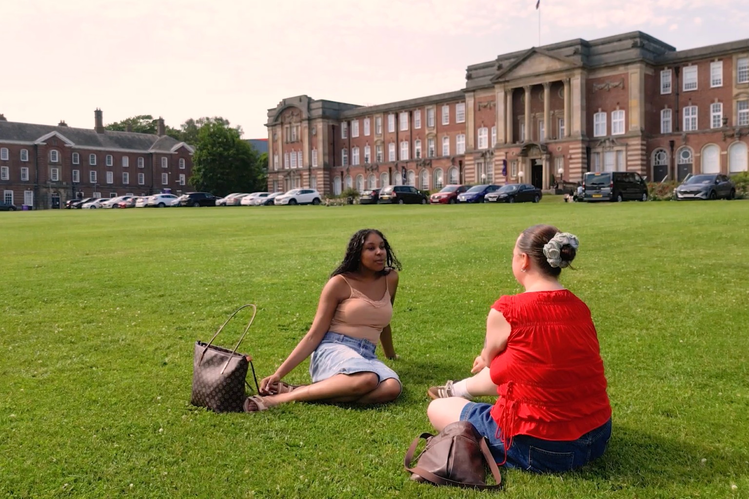 Student Ambassador speaking to staff member on grass outside of Leeds Beckett University.
